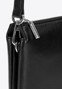 Borsa a mano in pelle nera con materiale testurizzato, rifiniture in argento e una cerniera con una targhetta con la scritta "WITCHEEN".