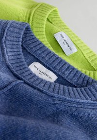 Divi džemperi, kas izgatavoti no 100% aitu vilnas. Viens ir spilgti zaļš, otrs ir zils. Abiem ir ribotas apkakles un kopšanas etiķetes.