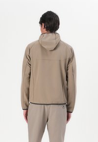 Beige hoodie gemaakt van gladde stof, met een getailleerd ontwerp, elastische boorden en subtiele logo's op de achterkant en onderkant.