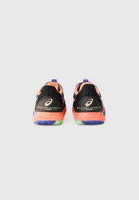 Baskets de sport noires avec des accents orange néon, semelle extérieure verte et bleue, talon renforcé et détails de logo sur les côtés.