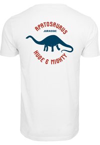 Valkoinen T-paita, jossa on sininen Apatosaurus -grafiikka selkäpuolella, punaisella tekstillä "JURASSIC" ja "HUGE & MIGHTY" ympyrämuodostelmassa.