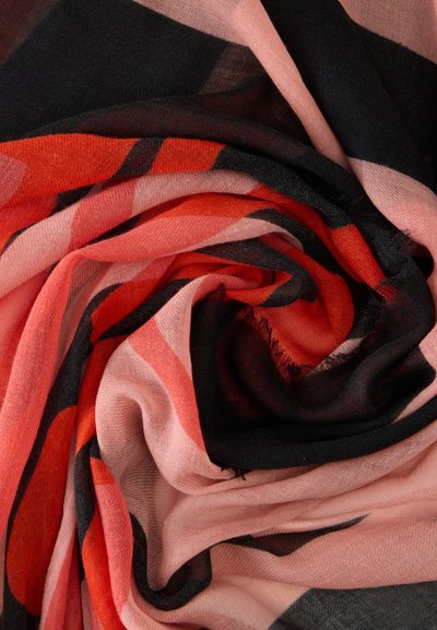 Tissu doux plié en motif spirale avec des rayures audacieuses dans des tons de rose, rouge, noir et corail.