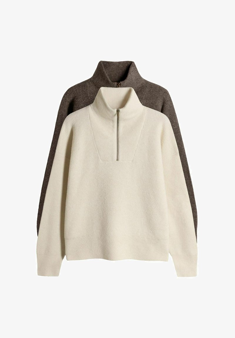 Kaksi kaulustakkia pinottuna; yksi kerma värinen, jossa on teksturoitu ribbikuvio ja vetoketjukaulus, ja toinen tummanruskea, jonka pinta on sileä.