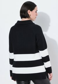 Zwart-witte gestreepte gebreide trui met een sjalkraag, featuring brede horizontale strepen en een losse pasvorm met zijsplitten.