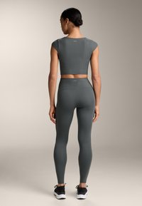 Set di top corto a coste grigio scuro e leggings con una vestibilità aderente. Il top ha maniche corte, mentre i leggings presentano una vita alta.