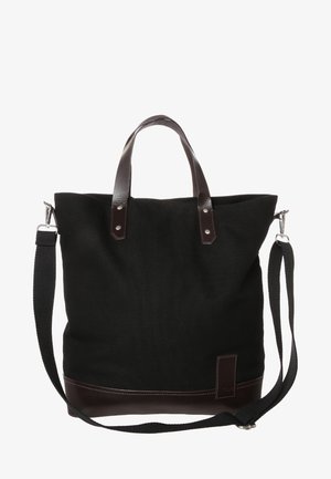 Zwarte canvas boodschappentas met bruine leren accenten, stevige bovenhandgrepen, verstelbare schouderriem en een vlakke bodem voor stabiliteit.