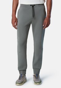 Graue Baumwoll-Sweatpants mit einem Kordelzug-Bund, Seitentaschen und gerippten Bündchen; zeigt dezente Gebrauchsspuren entlang der Beine.