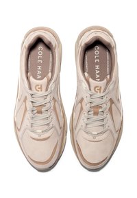 Scarpe da ginnastica beige chiaro con una tomaia in rete e suede, caratterizzate da accenti tonali, lacci in tessuto e una suola realizzata in gomma di tarassaco.