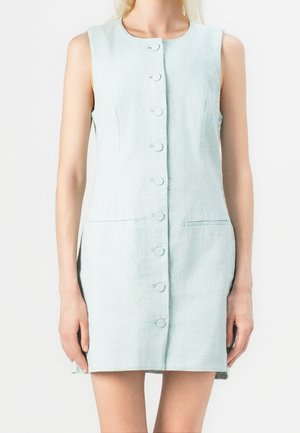 Robe bleu clair sans manches avec des boutons ronds sur le devant et deux poches fendues horizontales au niveau des hanches.