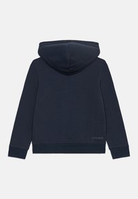 Kraljevo modra kapuca, mehka tkanina, z izrazito kapuco, dolgimi rokavi, rebrastimi manšetami in majhnim logotipom blizu roba.