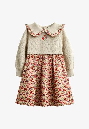 Kremfarvet strikket sweaterkjole med diamantmønster, flæset blomsterkrave, lille blomsterbroderi og en samlet blomster nederdel i røde og lilla toner.