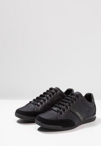 Czarne sneakersy z połączenia gładkiego materiału syntetycznego i teksturowanej zamszowej powierzchni. Wiązane z subtelnym logo z boku.