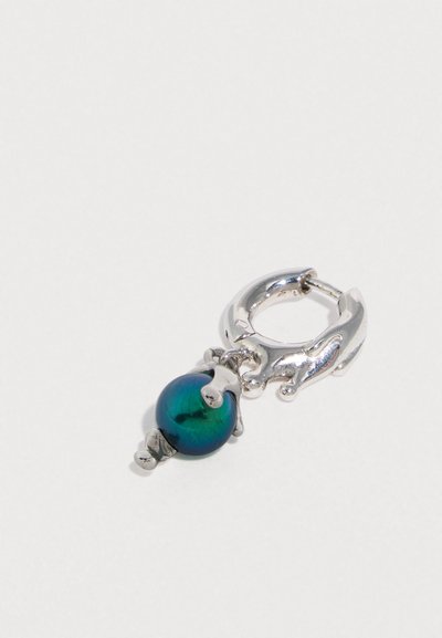 Ασημένιο σκουλαρίκι κρίκος με πράσινη ιριδίζουσα χάντρα. Υφή στην επιφάνεια, οβάλ σχήμα και προσαρτημένα διακοσμητικά στοιχεία.