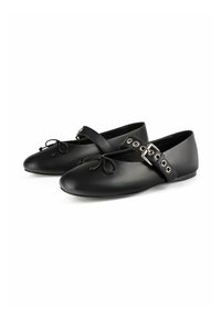 Zapatos planos de cuero negro con punta redondeada, lazada decorativa y una correa ajustable con hebilla de plata y ojales.