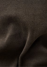 Bruine geribde stof met een gladde textuur, die verticale lijnen en een lichte glans toont, opgevouwen om diepte en dimensie te creëren.