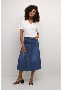 Denim maxi rok met knoopsluiting aan de voorkant, zijzakken en een uitlopende silhouet; gecombineerd met een wit gestreept V-hals t-shirt.