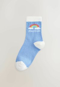 Lyseblå sok med hvid tå, hæl og manchet, med en regnbue over skyerne og ordet "FREITAG" nedenfor på ankelområdet.