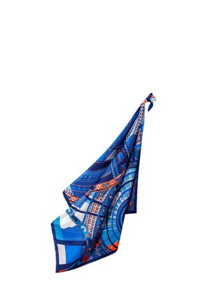 Écharpe en soie bleue avec des motifs géométriques et floraux complexes dans des nuances de bleu, blanc et orange, nouée à un coin.
