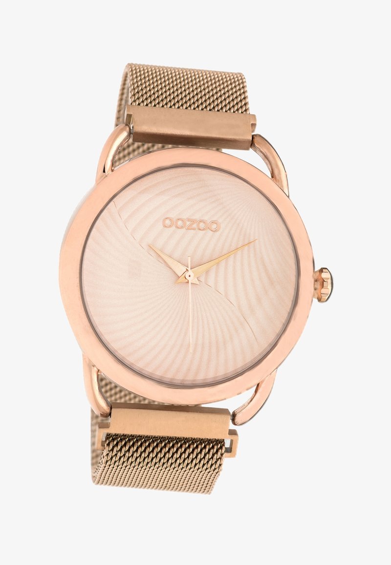 Montre ronde en or rose avec un cadran beige texturé, des aiguilles dorées et un bracelet en maille métallique. Elle dispose d'un fermoir simple pour l'ajustement.