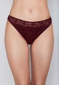 Burgundy lace thong featuring intricate floral patterns, a semi-sheer texture, and a delicate waistband with a small decorative accent.