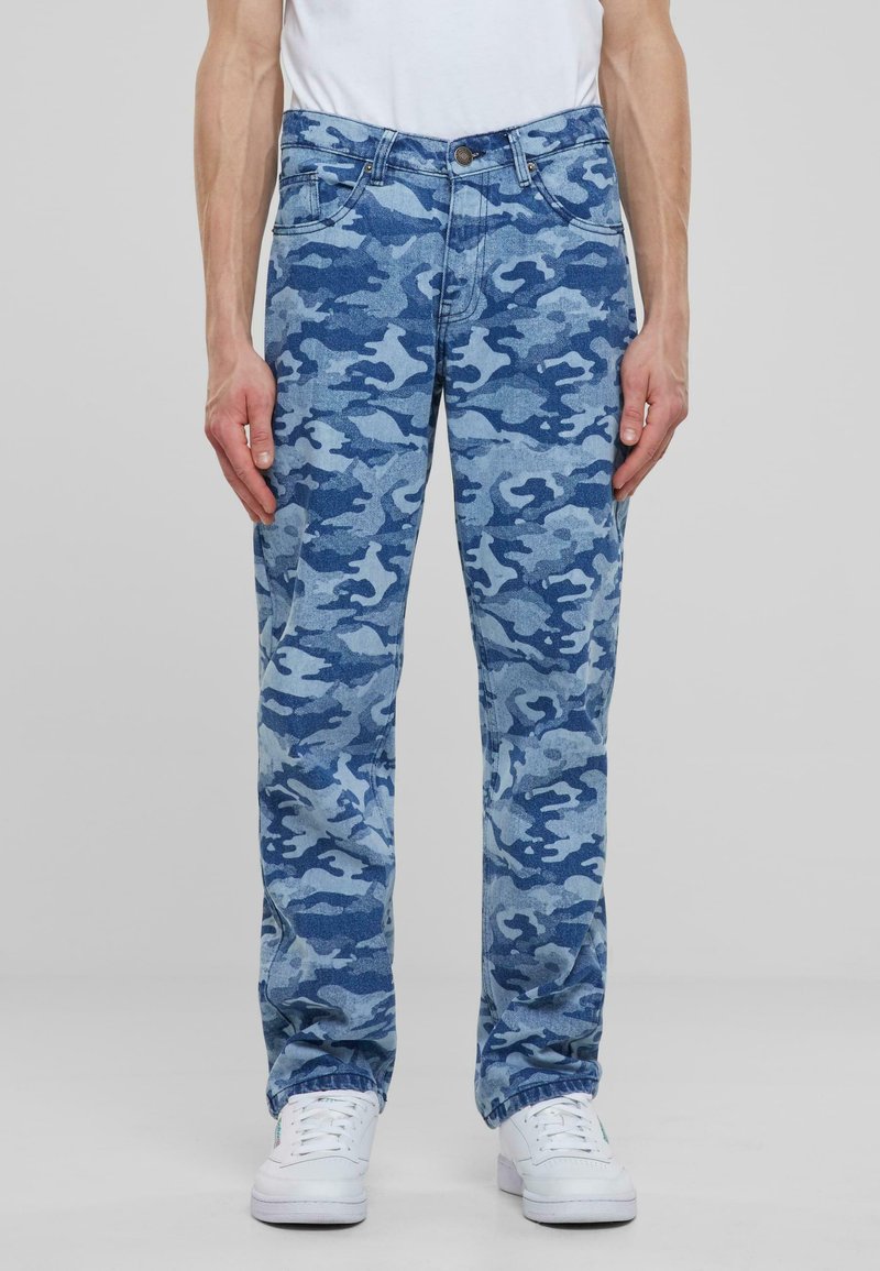 Jeans de camuflaje azul en un tejido de denim deslavado con un corte relajado, que cuentan con un diseño clásico de cinco bolsillos y un cierre de botón.