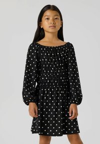 Czarna sukienka w kropki z zebranym dekoltem i długimi bufkami. Posiada elastyczny pas i rozkloszowany krój spódnicy. Gładka faktura.
