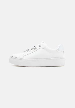 White sneaker with a smooth leather upper, rounded toe, metal eyelets, and a textured rubber sole. Features a subtle silver accent at the heel.