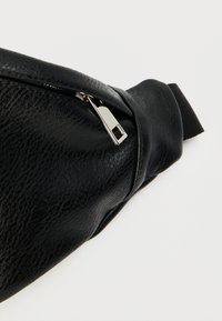 Μαύρο τσαντάκι μέσης από συνθετικό δέρμα με υφή, με ασημί φερμουάρ και μαλακό λουρί.