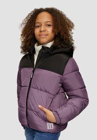 Doudoune violette avec une partie supérieure noire, dotée d'une fermeture éclair, d'une capuche et de poches latérales. Portée par-dessus un pull léger.
