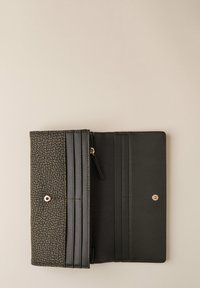 Portafoglio rettangolare aperto, nero e marrone, con texture, che mostra diversi scomparti per carte e un piccolo vano con zip su una superficie beige.
