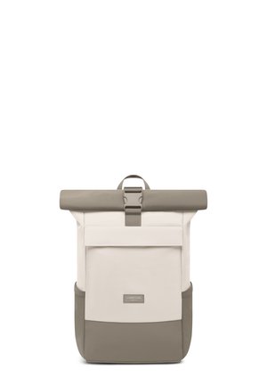 Béžový a taupe batoh s rolovacím vrchom, predným vreckom na klopu a bočnými sieťkovými vreckami, zabezpečený stredovým prackovým popruhom.
