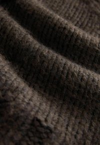 Dark brown, textured wool fabric with a ribbed pattern, showing fine fibers and gentle folds, emphasizing softness and depth.