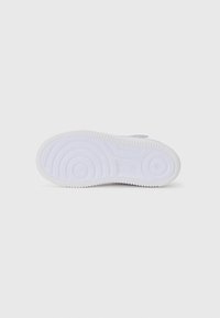 Semelle de sneaker en caoutchouc blanc avec des motifs de semelle circulaires, présentant un bord texturé et une zone centrale lisse, conçue pour la traction et la durabilité.