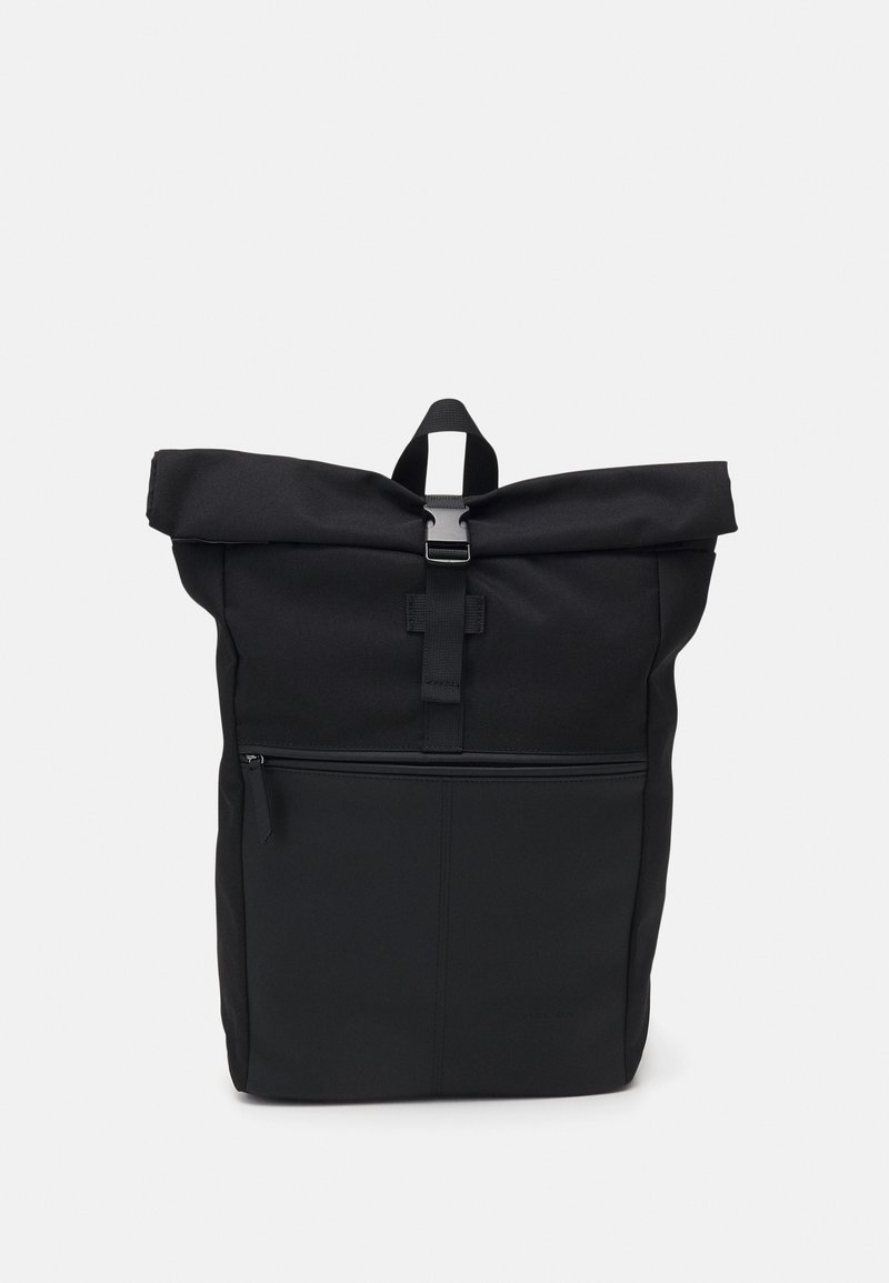 Sac à dos noir à rabat enroulable avec poche zippée sur le devant et fermeture à boucle en plastique sur fond blanc.