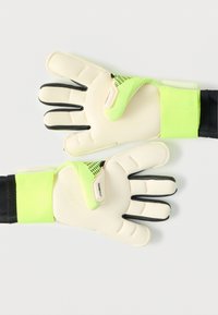 Γάντια τερματοφύλακα με ανοιχτόμπεζ παλάμη, μαύρα δάχτυλα και έντονες πράσινες λεπτομέρειες. Υφή στην επιφάνεια και στερεή ρυθμιζόμενη μανσέτα στον καρπό.