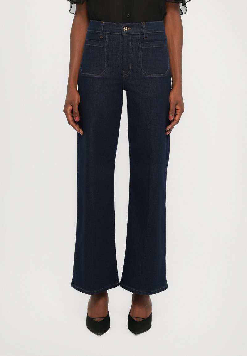 Dark blue wide-leg jeans with a high waist, five pockets, and contrasting stitching details. Fabric has a smooth, sturdy texture.