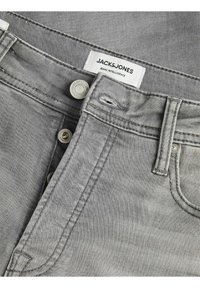 Szare dżinsy z denimu o klasycznym fasonie z pięcioma kieszeniami, rozpięciem na guziki i markową metką. Materiał ma gładką, lekko teksturowaną powierzchnię.