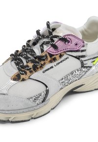 Baskets chunky avec un mélange de maille blanche, des accents argentés, un panneau imprimé léopard, des lacets noirs et une semelle pailletée. Détails de marque.