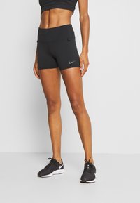 Svarta högmidjade träningsshorts med en slät yta och en Nike swoosh-logotyp. Bärs med svarta sportskor.