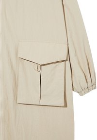 Veste beige à manches longues avec poignet élastique et grande poche avant avec rabat et détail plis.