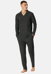 Dunkelgraues Loungewear-Set bestehend aus einem langärmligen, kragenlosen Oberteil und passenden Hosen. Hergestellt aus weichem Material, mit lockerer Passform und schlichter Gestaltung.
