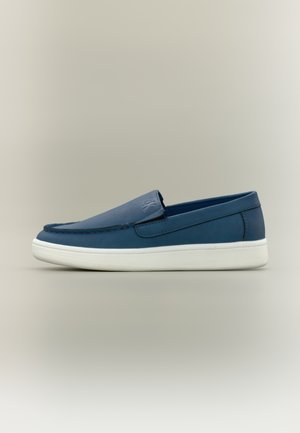 Blaue Slipper mit glattem Lederfinish, weißer Gummisohle und Nahtdetails entlang der oberen Kante und vorne. Minimalistisches Design.