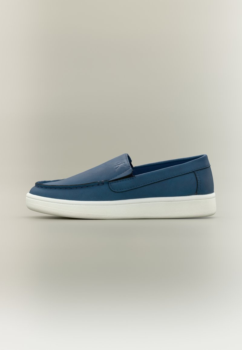 Chaussures bleu à enfiler avec une finition en cuir lisse, semelle en caoutchouc blanche et détails de couture le long du bord supérieur et de l'avant. Design minimaliste.