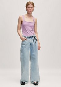 Lavendel vierkante hals tanktop gecombineerd met lichtblauwe wijde jeans, met een trekkoord in de taille en een relaxte pasvorm. Zwarte ballerina's maken de look compleet.