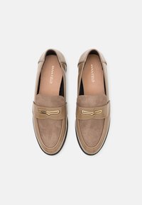 Hnědé kožené loafers s lesklým povrchem a semišovým panelem. Obsahují zlatý přední akcent a gumovou podrážku.