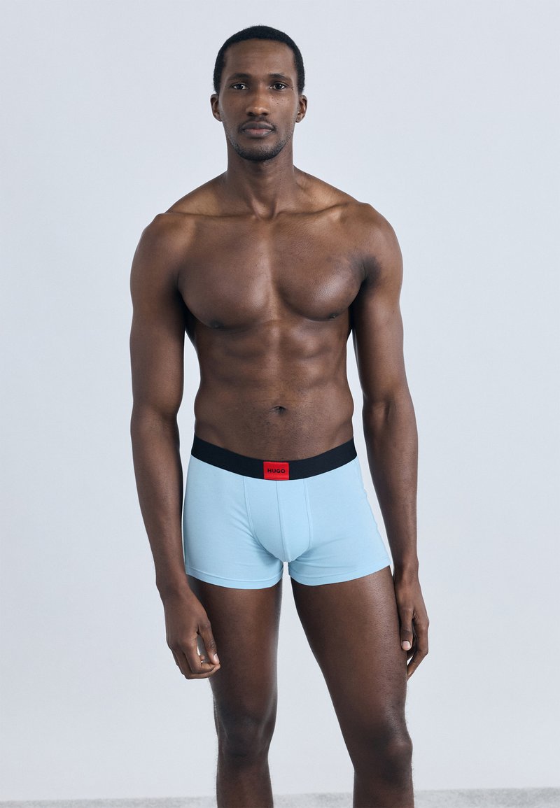 Ανοιχτό μπλε μποξεράκια με μαύρη μέση που έχει κόκκινη ετικέτα. Το ύφασμα είναι λείο, εφαρμοστό και ελαστικό για άνεση.