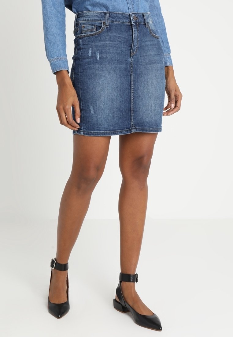 Jupe crayon en denim bleu moyen avec des accents déchirés, présentant un design ajusté, cinq poches et une longueur mi-cuisse.