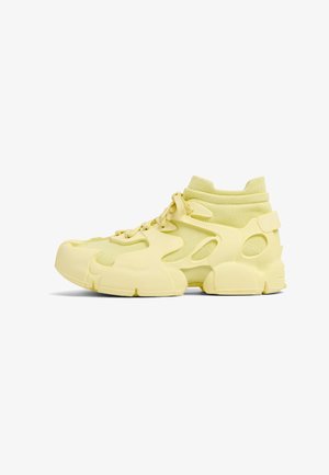 Zapatillas altas amarillas con una parte superior texturizada, paneles de malla y cortes únicos en un diseño moldeado con un cuello acolchado.