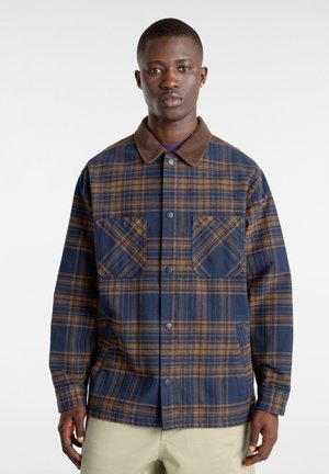 Geruite shirt in blauw en bruin, gemaakt van zacht weefsel, met een bruine kraag, twee borstzakken en drukknoopsluitingen.