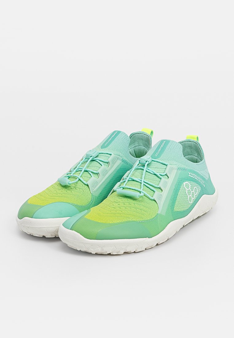Zapatillas deportivas ligeras en verde y amarillo con tejido texturizado, cierre de cordones en la parte delantera y suela de goma blanca flexible. Logotipo destacado en el lado.